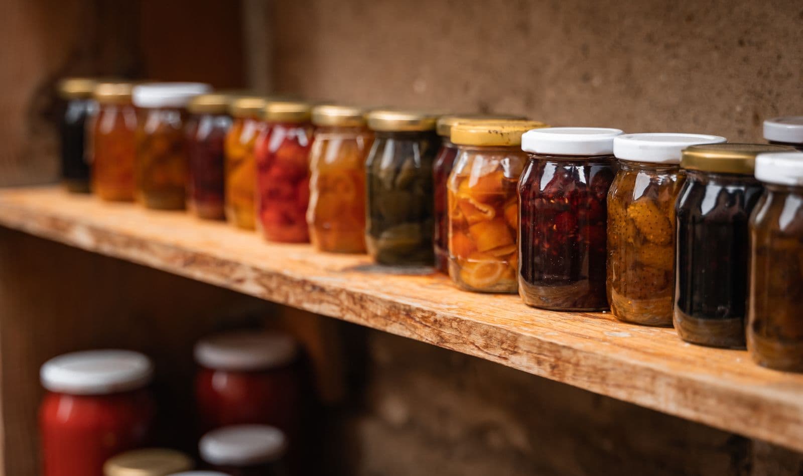 Jars of home preserves on a wooden shelf